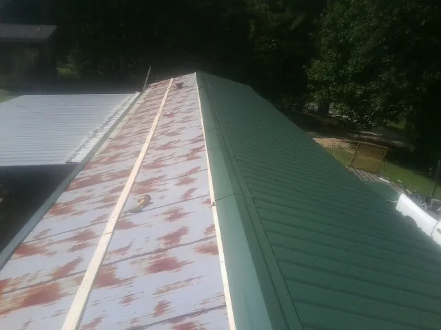 Old rusted panels beside newly installed green metal roofing — Wind Damage Roof Repair by Roofing Brothers in West Bloomfield